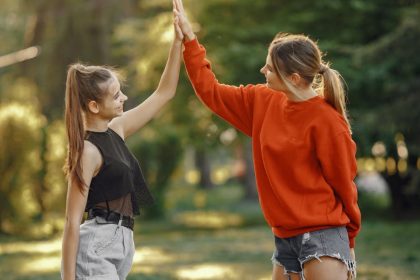 Two women enjoying a sunny day in the park with a joyful high five.