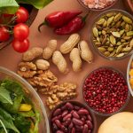 Explore a colorful assortment of healthy ingredients, featuring vegetables, nuts, seeds, and spices in a top view layout.