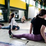 Women engaging in a group stretching session in an indoor gym.