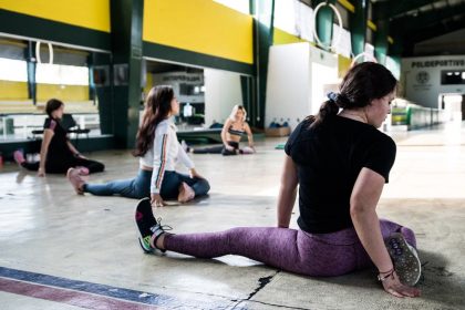 Women engaging in a group stretching session in an indoor gym.